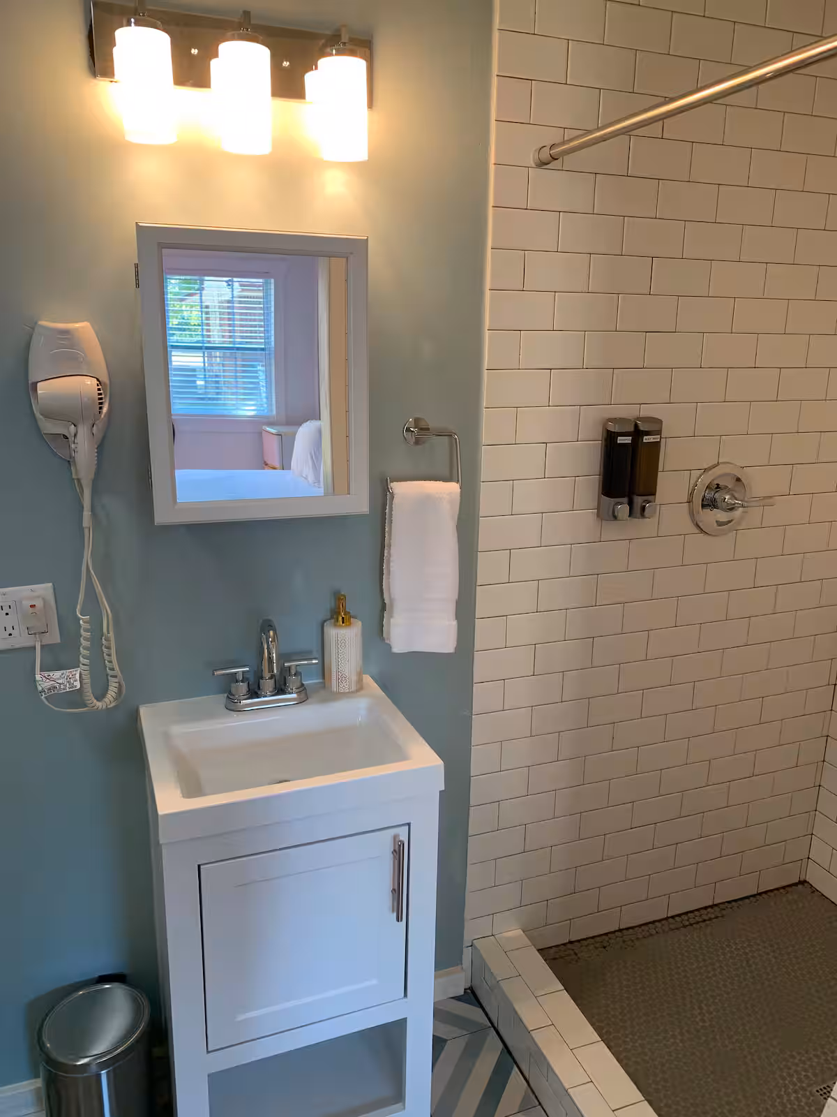 Bathroom with sage walls, geometric floor tile, white vanity, and colorful wall art