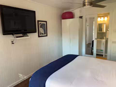 Bedroom sitting area with TV, navy waffle-knit throw, view into bathroom