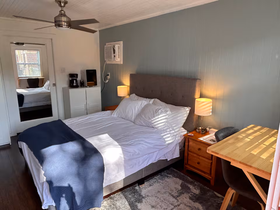 Wider bedroom view showing coffee station, dark hardwood floors, and cozy seating area